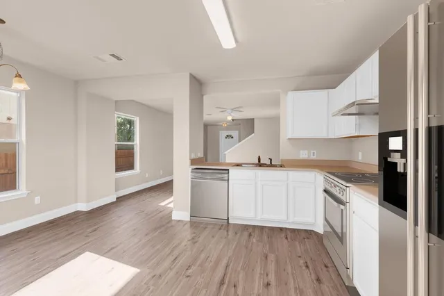 a kitchen with a white cabinets and wooden floor