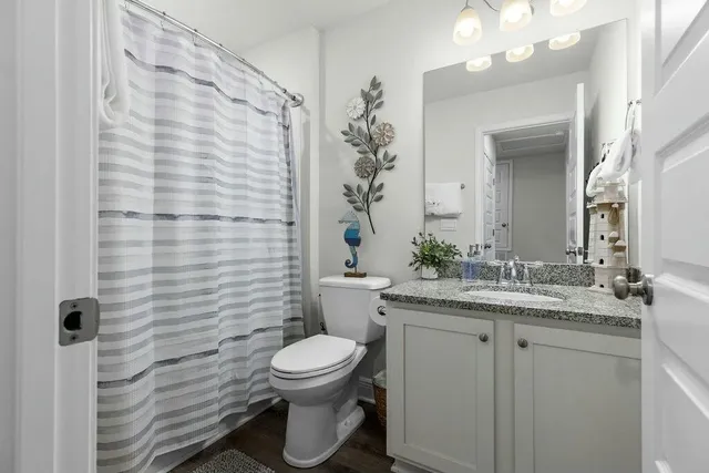 a bathroom with a granite countertop sink a toilet and a mirror