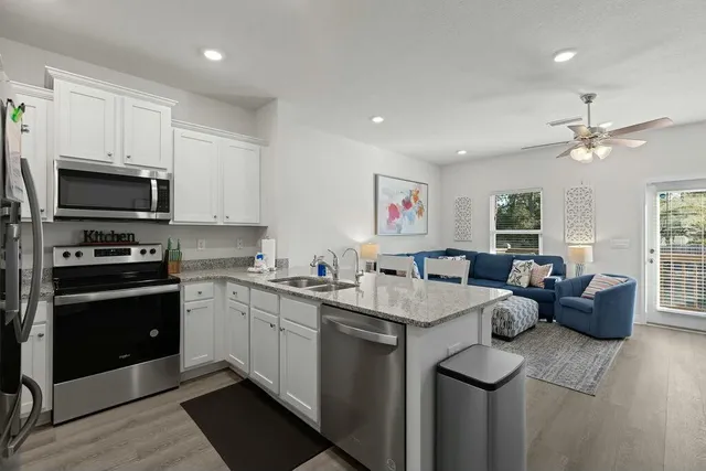 a open kitchen with stainless steel appliances granite countertop a sink dishwasher a stove and a refrigerator with wooden floor