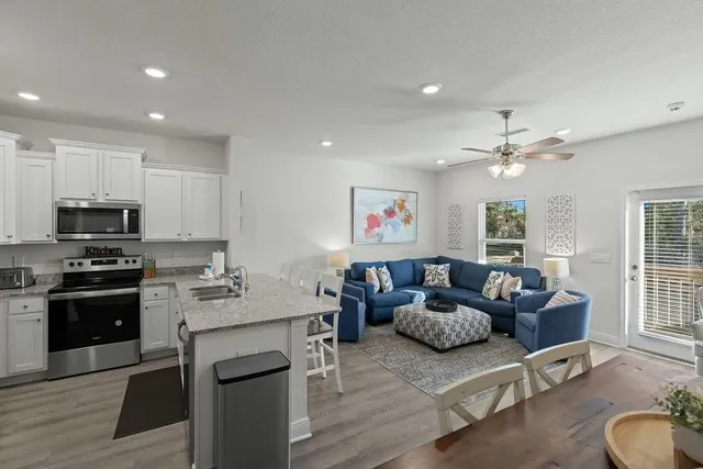 a living room with furniture kitchen and a wooden floor