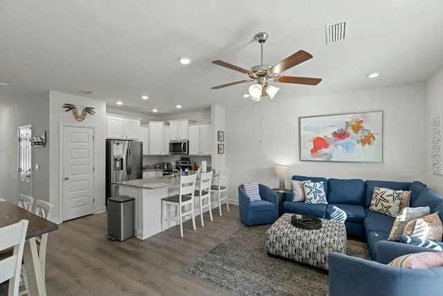 a living room with furniture kitchen view and a chandelier