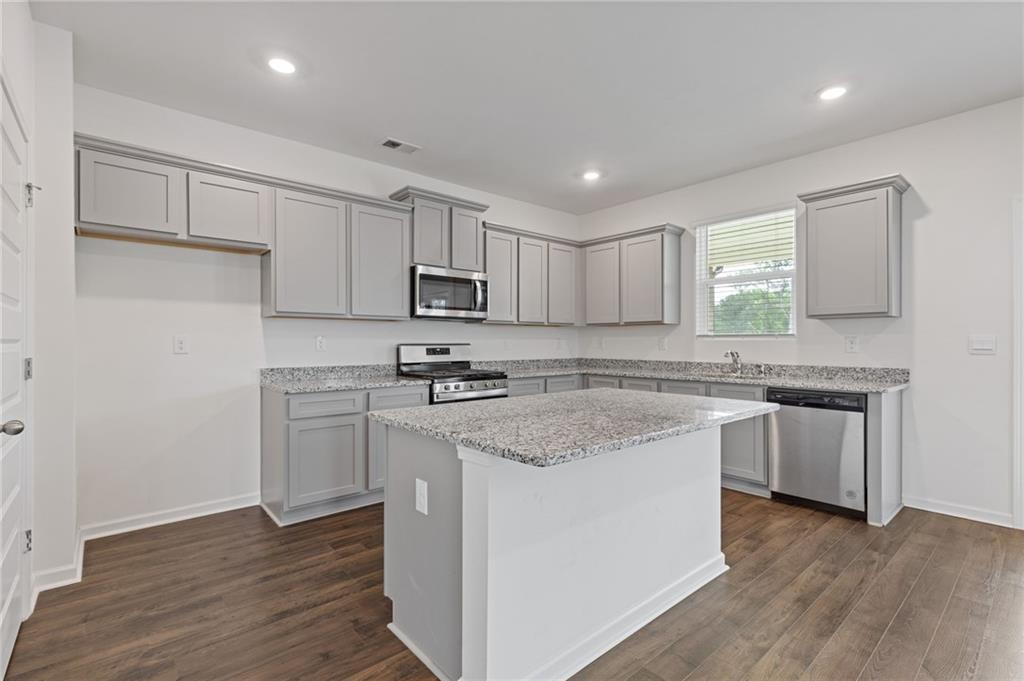 294 Ralph Still Road Dacula, GA 30019 - Photo 11 of 55 a kitchen with stainless steel appliances granite countertop a sink a stove a refrigerator and white cabinets