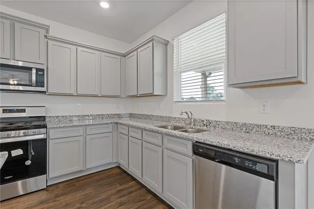 a kitchen with stainless steel appliances granite countertop a sink dishwasher a stove and a microwave oven with cabinets