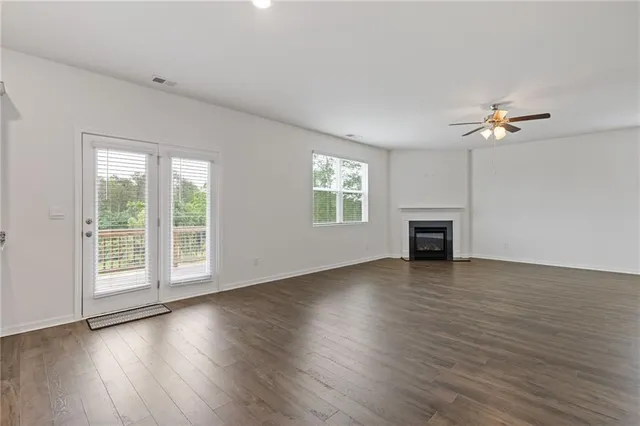 an empty room with wooden floor fan and windows