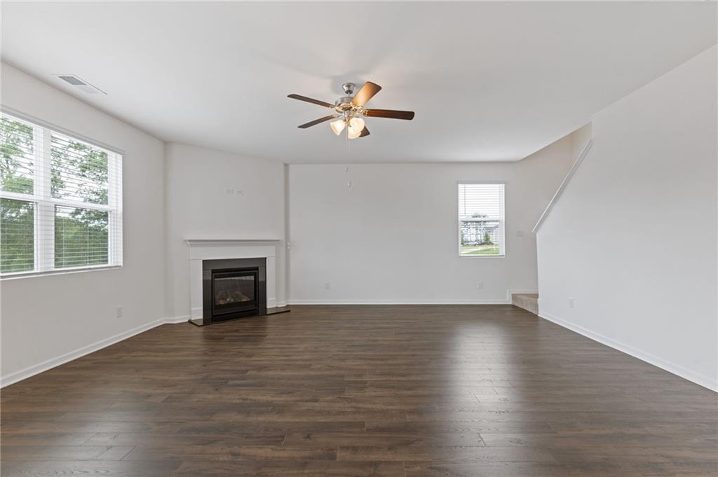 294 Ralph Still Road Dacula, GA 30019 - Photo 19 of 55 an empty room with wooden floor chandelier fan and windows