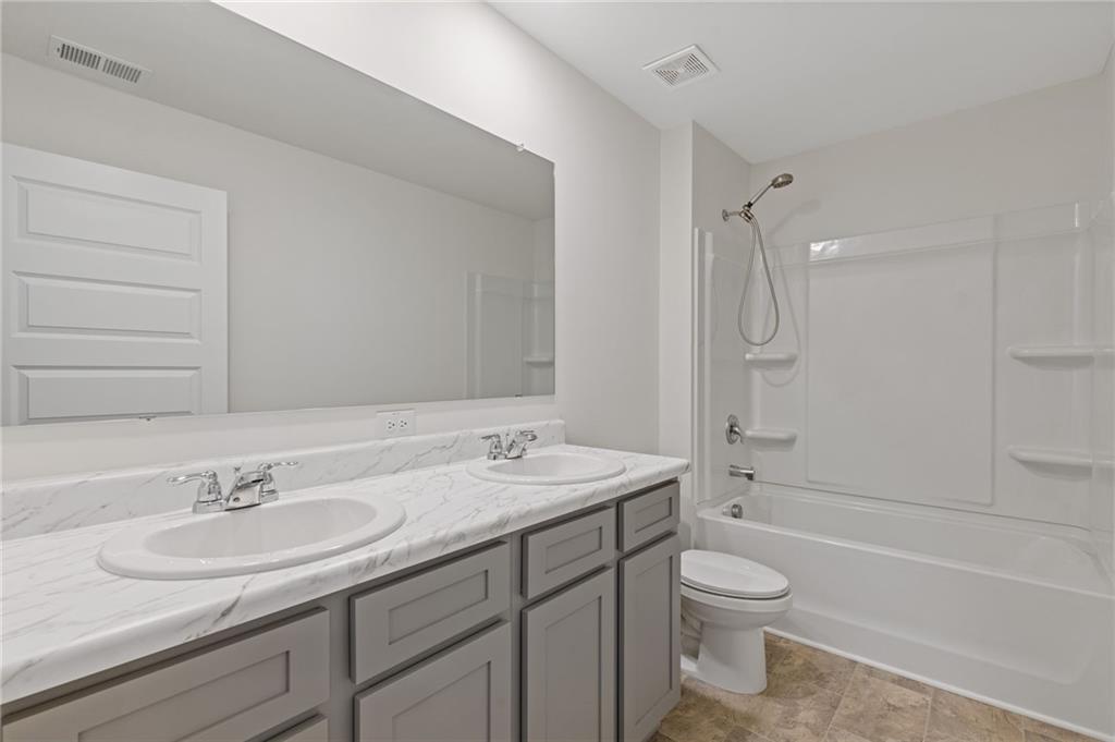 294 Ralph Still Road Dacula, GA 30019 - Photo 26 of 55 a bathroom with a granite countertop sink a toilet and a bathtub