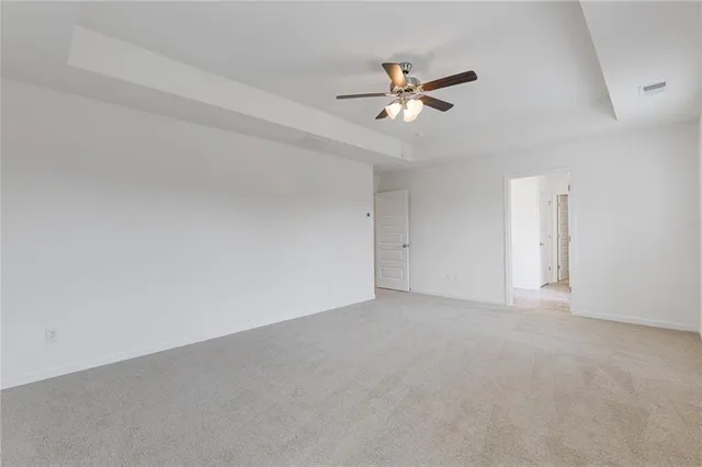 a view of an empty room with chandelier fan