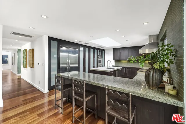 a kitchen with stainless steel appliances granite countertop a kitchen island a stove a sink a refrigerator and a dining table