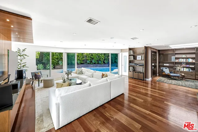 a living room with furniture floor to ceiling window and wooden floor