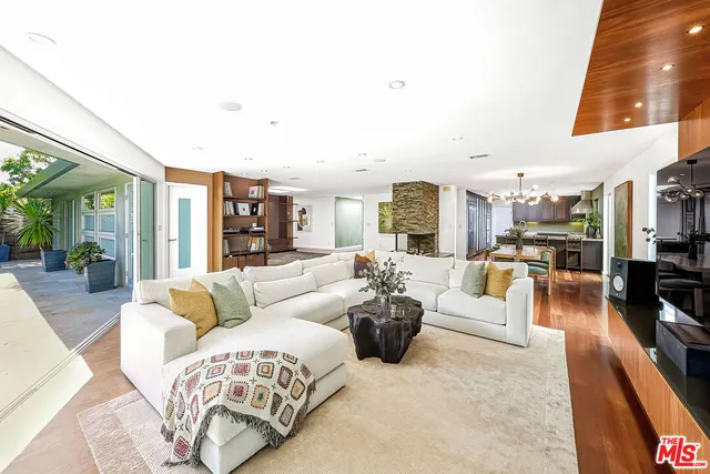 a living room with furniture a wooden floor and next to a dining table