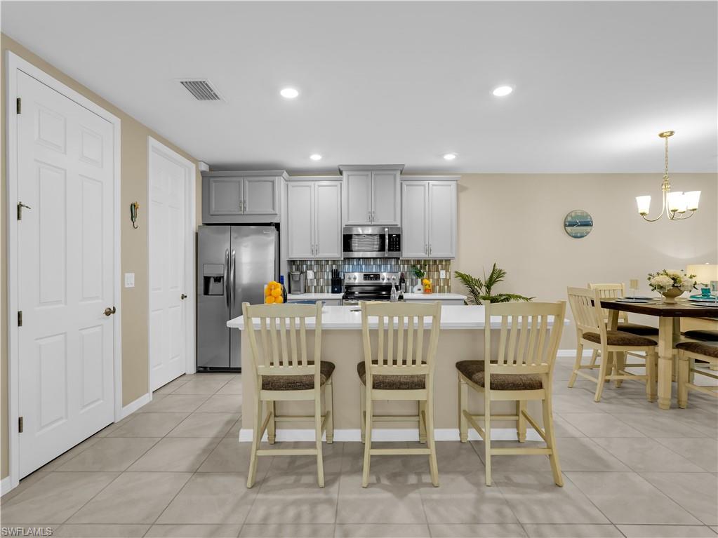14695 Edgewater Circle Naples, FL 34114 - Photo 11 of 39 a kitchen with stainless steel appliances kitchen island granite countertop a refrigerator a stove a dining table and chairs