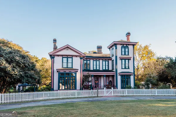 a view of a big house with a big yard and large trees