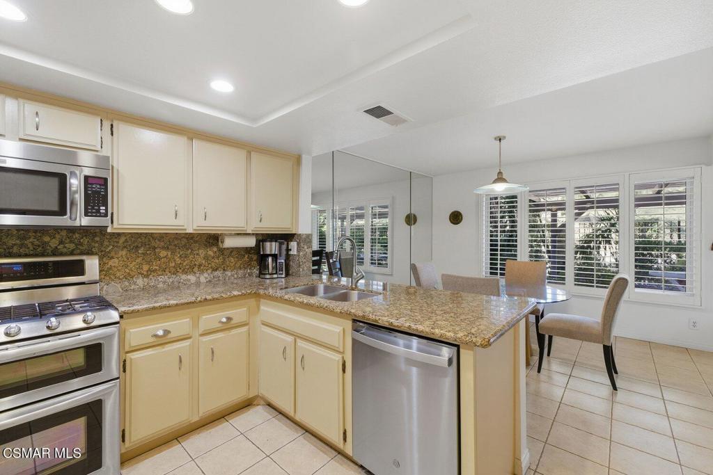 19137 Index Street, Unit 9 Porter Ranch, CA 91326 - Photo 13 of 39 a kitchen with stainless steel appliances granite countertop a stove a sink dishwasher a microwave oven with white cabinets and wooden floor