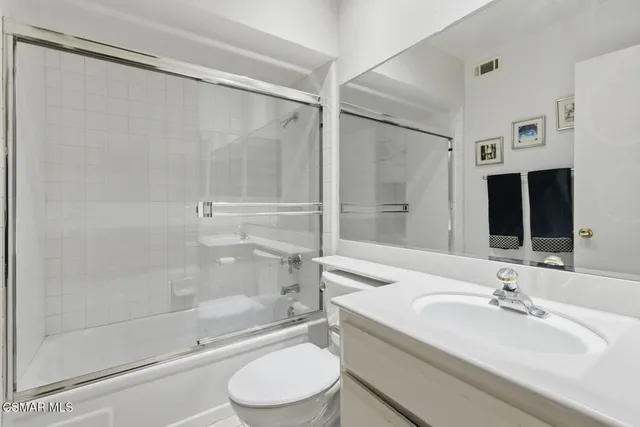 a bathroom with a granite countertop sink toilet and a mirror