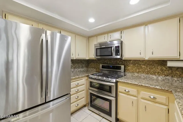 a kitchen with granite countertop a refrigerator stove and microwave