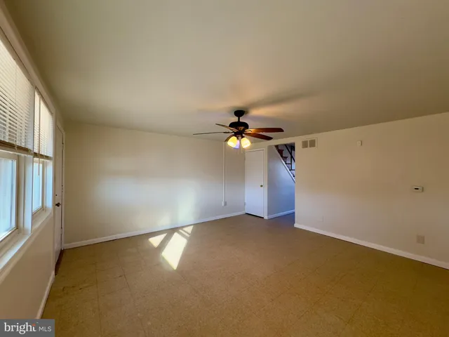 an empty room with windows and chandelier fan
