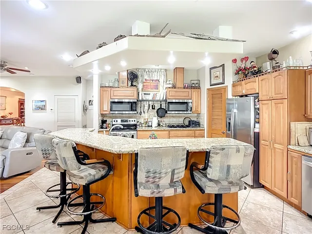 a kitchen with stainless steel appliances kitchen island granite countertop a table chairs and a refrigerator