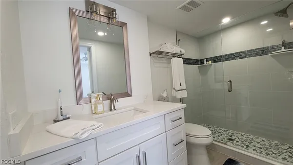 a bathroom with a granite countertop sink a toilet and shower
