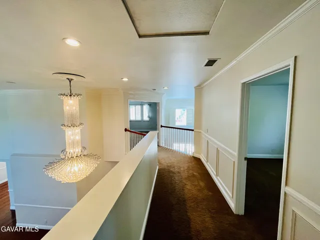 a view of a hallway with wooden floor and a living room