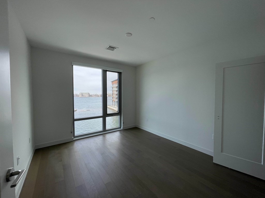 45 Lewis Street, Unit 310 Boston, MA 02128 - Photo 7 of 11 an empty room with wooden floor and windows