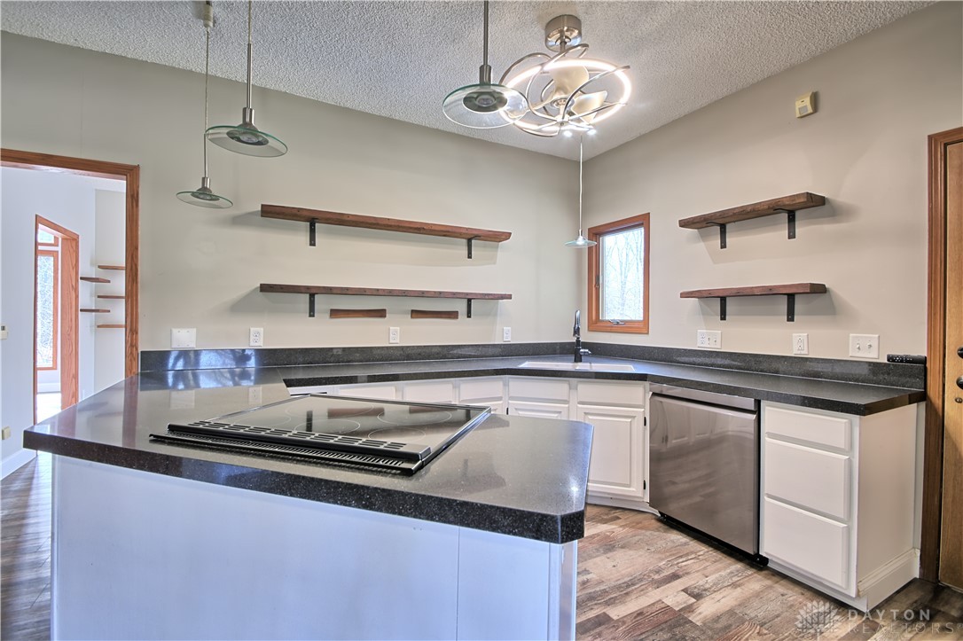 8711 Nicole Lane Springboro, OH 45066 - Photo 12 of 87 This modern kitchen features a sleek island cooktop and open shelving, perfect for culinary enthusiasts.