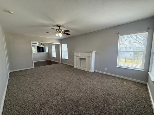 an empty room with windows and fireplace