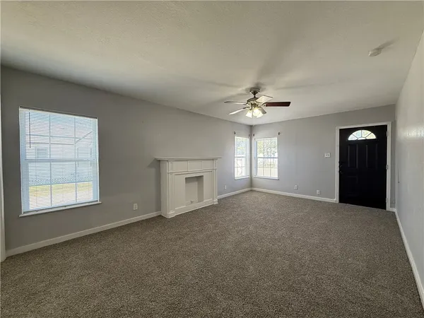 en empty room with windows and chandelier fan