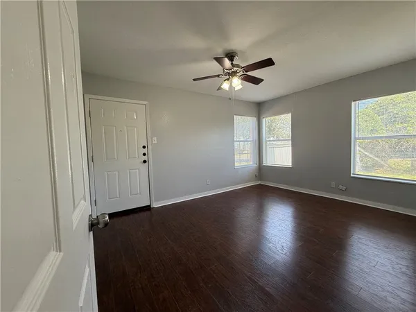 a view of empty room with wooden floor and fan