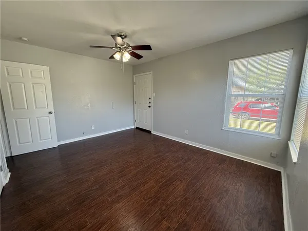 a view of an empty room with wooden floor and a window
