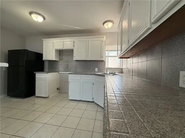 a kitchen with a sink a refrigerator and cabinets