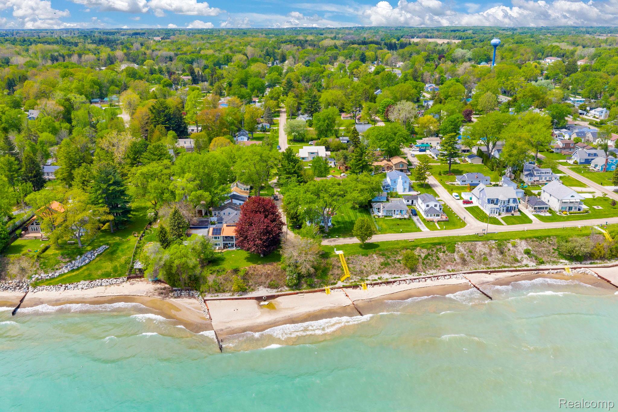 7489 Aspen Road Lexington, MI 48450 - Photo 59 of 62 Aerial perspective showcasing properties along a lakefront, featuring sandy beaches and residential structures