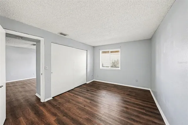 an empty room with wooden floor cabinet and windows