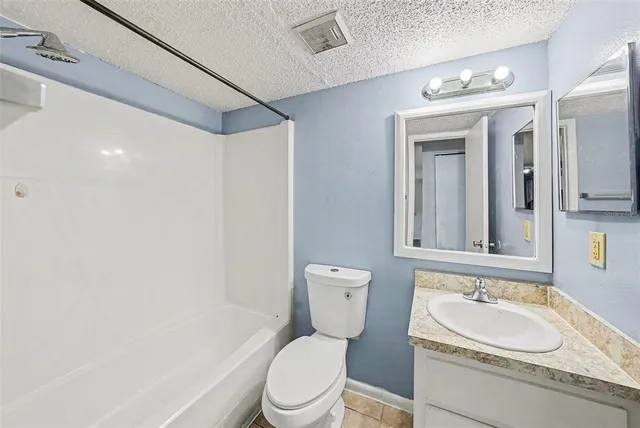 a bathroom with a granite countertop sink a toilet and a mirror
