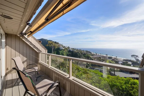 a view of a balcony with wooden chairs and floor and wooden fence