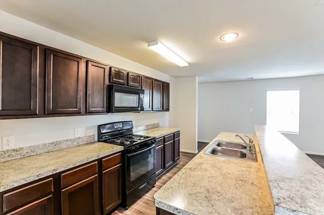 a kitchen with granite countertop wooden cabinets and black appliances