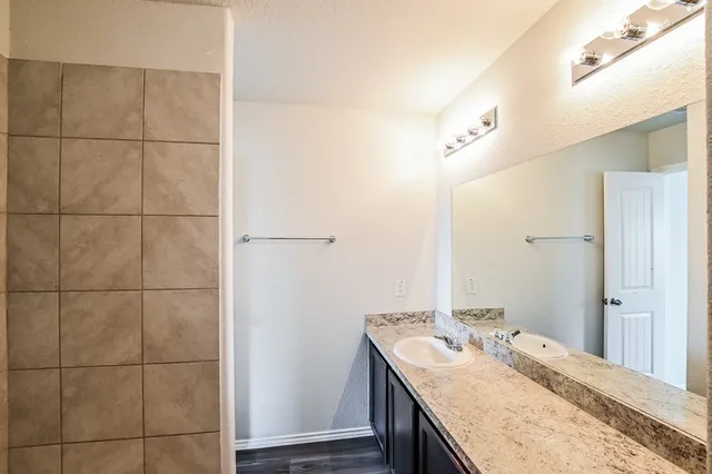 a bathroom with a granite countertop sink a shower and a mirror