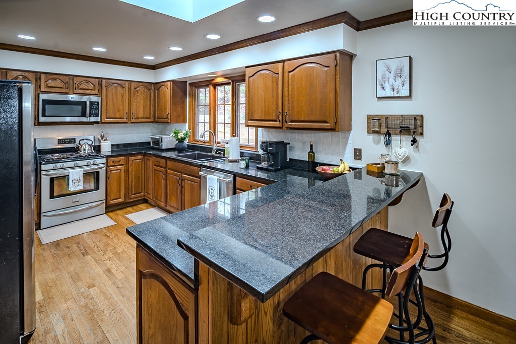 281 Old Hartley Road Banner Elk, NC 28604 - Photo 13 of 50 a kitchen with stainless steel appliances granite countertop a stove top oven a sink a dining table and chairs with wooden floor