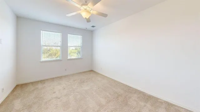 an empty room with windows and chandelier fan