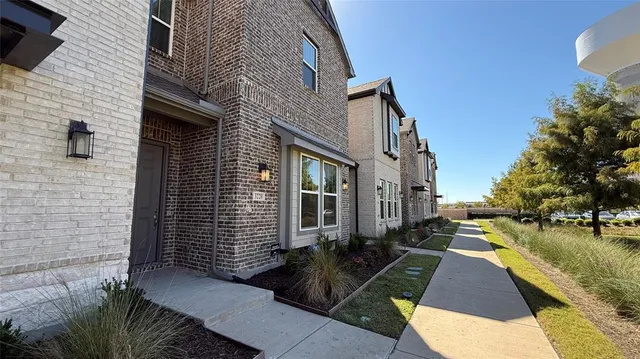 a view of a brick house with many windows next to a road