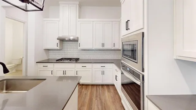a kitchen with granite countertop white cabinets and white appliances