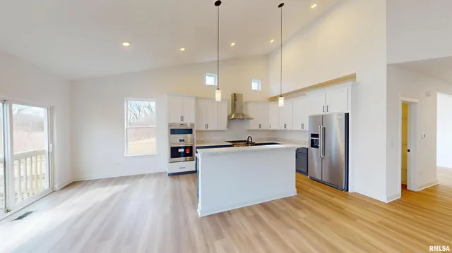 a kitchen with stainless steel appliances granite countertop a refrigerator a sink dishwasher and a wooden floor