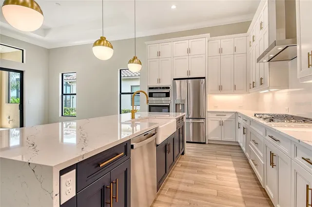 a kitchen with stainless steel appliances a sink dishwasher stove refrigerator and cabinets with wooden floor