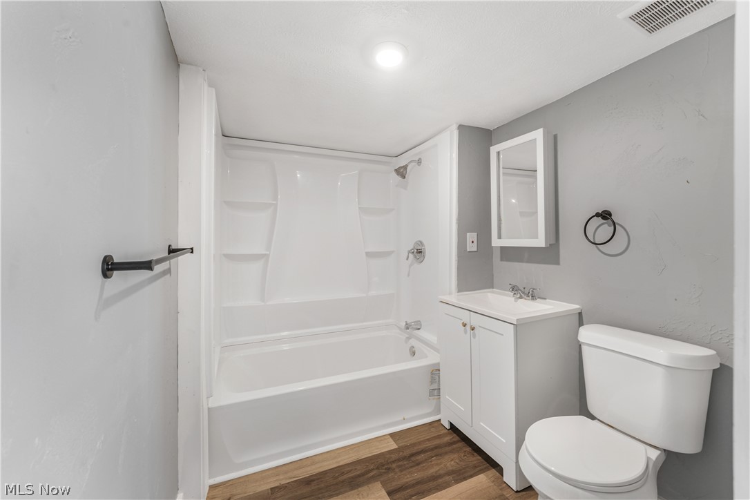 885 Wales Road Northeast Massillon, OH 44646 - Photo 20 of 34 Bathroom with a tub/shower combination, white vanity with integrated sink, wood-finish flooring, and a wall-mounted medicine cabinet
