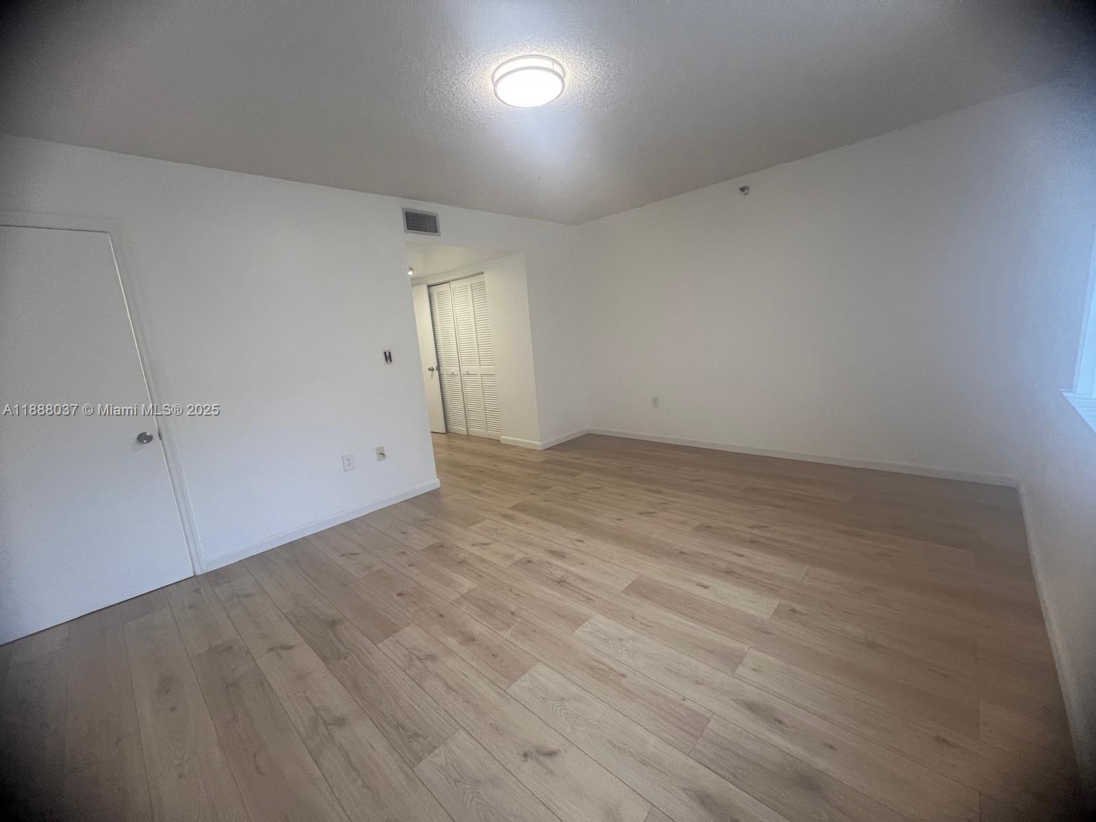 8900 Collins Avenue, Unit 203 Surfside, FL 33154 - Photo 8 of 11 an empty room with wooden floor and windows