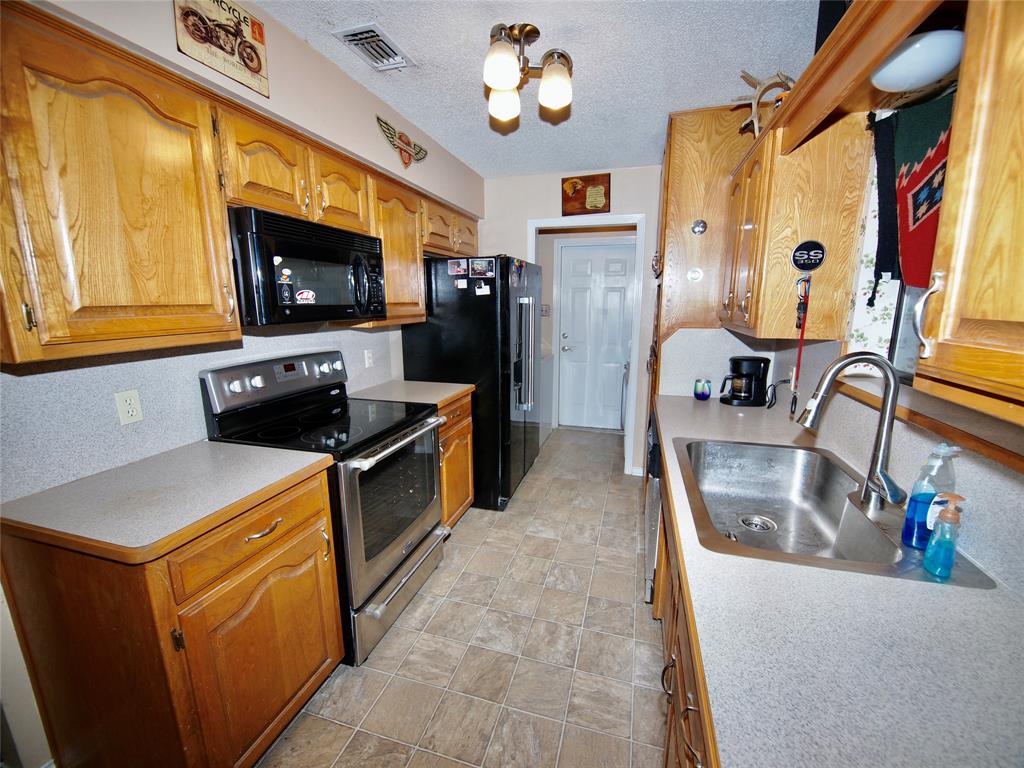 3106 South Lipsey Street Decatur, TX 76234 - Photo 6 of 27 a kitchen with stainless steel appliances granite countertop a refrigerator a stove top oven a sink and dishwasher