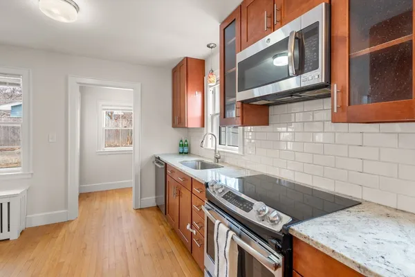 a kitchen that has a sink a stove and wooden floor