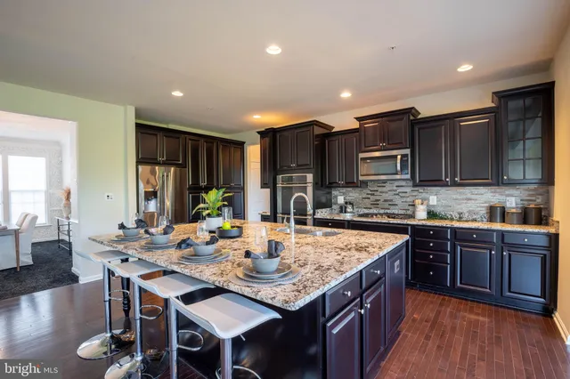a large kitchen with kitchen island granite countertop a sink a stove and chairs