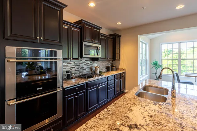 a kitchen with stainless steel appliances granite countertop a refrigerator stove and sink