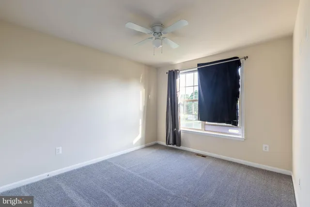 an empty room with a window and a ceiling fan