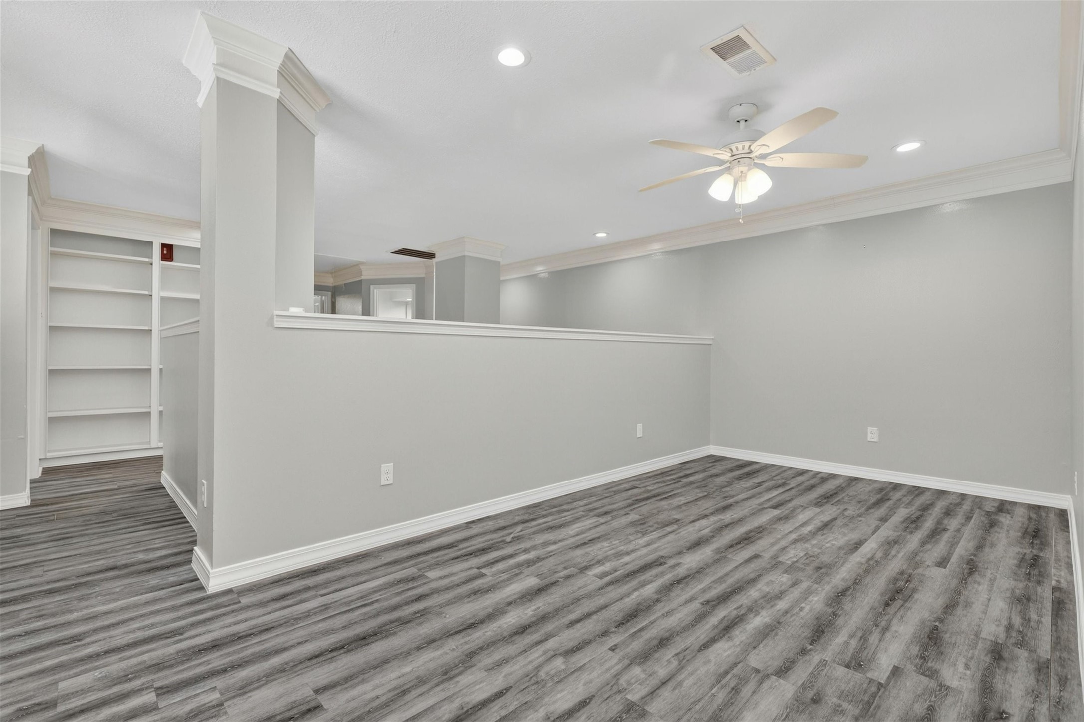 12929 Kingsbridge Lane Houston, TX 77077 - Photo 33 of 42 Expansive second-floor loft offering incredible flexibility for today’s modern lifestyle. This open-concept space is perfect for a game room, media room, home office, workout area, or additional living space. Buyers will love the custom built-in shelving, modern flooring, recessed lighting, and open overlook design that adds both character and functionality. The spacious layout and neutral designer colors create a bright, airy atmosphere ideal for entertaining or relaxing.